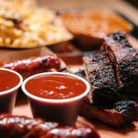 Large servings of barbecue, with pork ribs, sausage, macaroni and cheese, and baked beans.  Shot in Houston, Texas, USA.